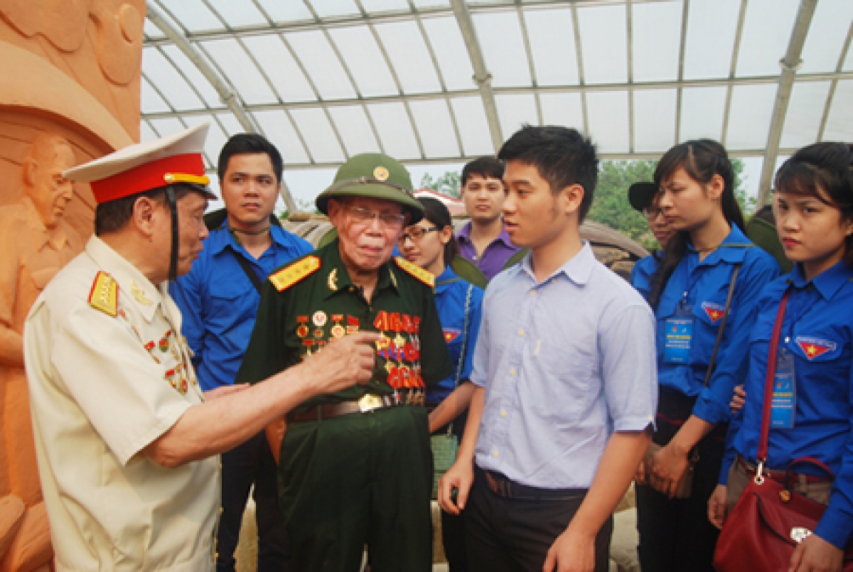 Cựu chiến binh Điện Biên Phủ nói chuyện với thế hệ trẻ bên di tích hầm Đờ Cát (Ảnh KT)
