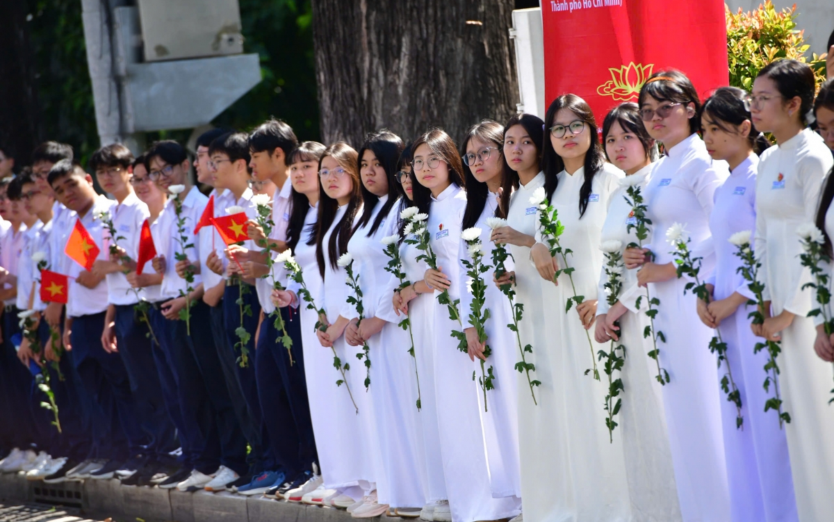 Người dân đứng bên đường, từ người già đến người trẻ, cả những bạn thanh thiếu niên, tay cầm hoa trắng, mắt ngấn lệ tiễn đưa 731 hài cốt liệt sĩ về nơi an nghỉ.