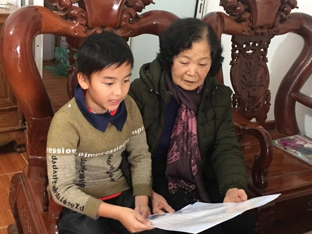 Cụ bà Trần Thị Bột kể cho cháu trai nghe về công việc ý nghĩa
