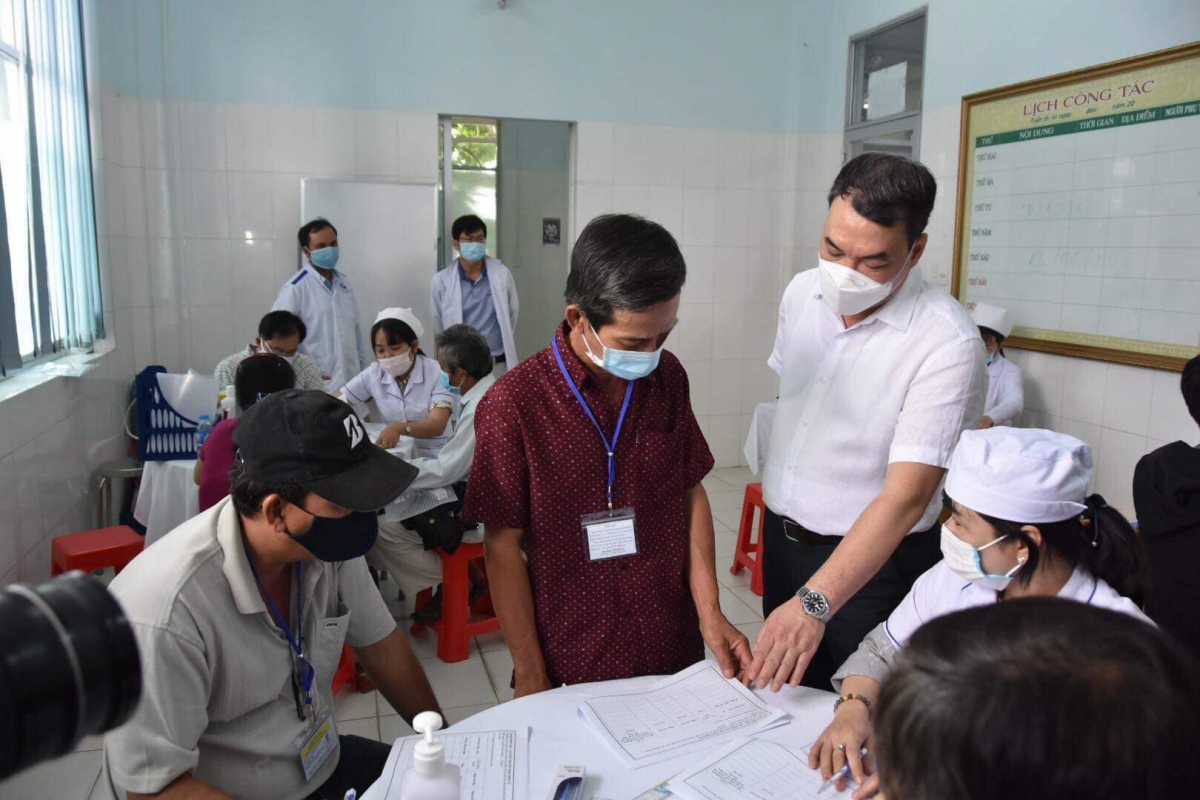 Tiến sĩ Nguyễn Ngô Quang, Phó Cục trưởng Cục Khoa học Công nghệ và Đào tạo, Bộ Y tế (người đứng, áo trắng) kiểm tra thủ tục trước khi tiến hành tiêm thử nghiệm.