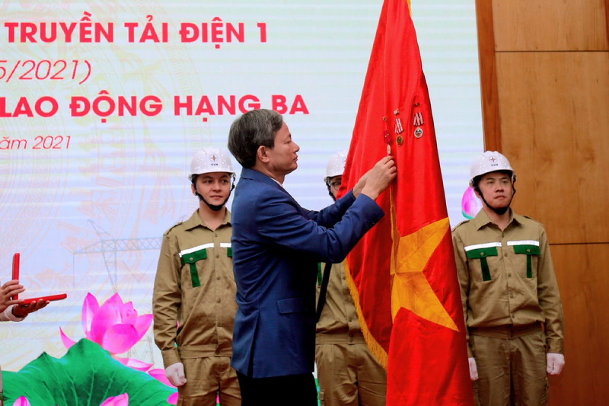 Ông Trần Đình Nhân - Tổng giám đốc Tập đoàn Điện lực Việt Nam (EVN) thừa ủy quyền của Chủ tịch nước gắn Huân chương Lao động hạng Ba lên lá cờ Tổ quốc, phần thưởng cao quý Đảng và Nhà nước trao tặng PTC1