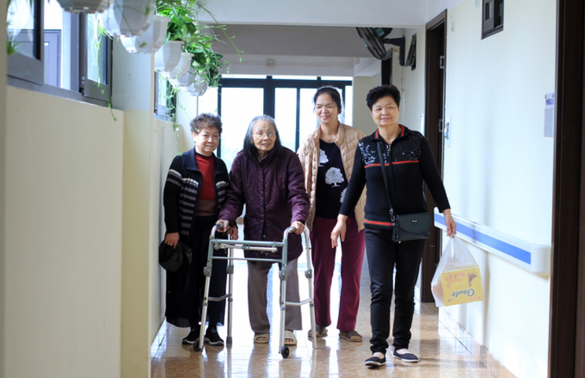 Những người hàng xóm tới thăm bà Nguyễn Thị Cận, 87 tuổi (chống gậy chữ u), tại một viện dưỡng lão ở Thanh Trì