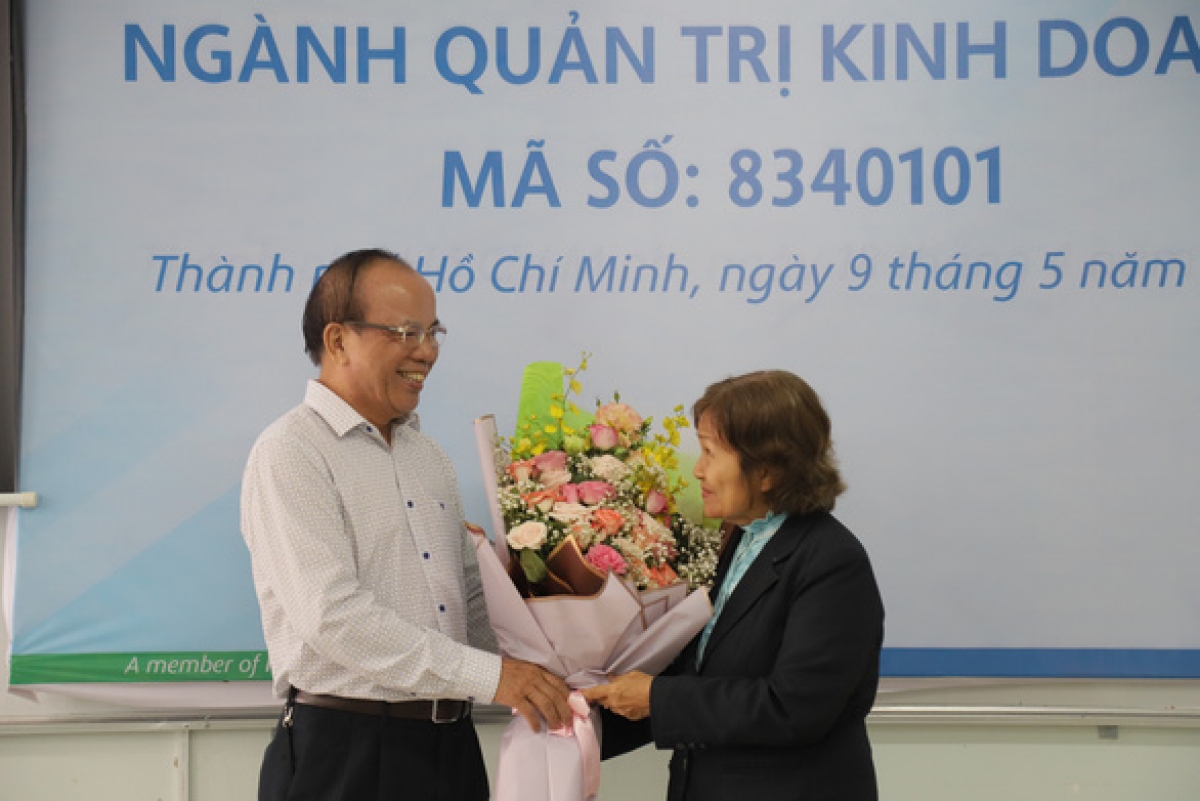 PGS.TS Trần Văn Thiện (đại diện Trường ĐH Văn Hiến) tặng hoa chúc mừng bà Phạm Kim Hoàng bảo vệ thành công luận văn thạc sĩ ở tuổi 71