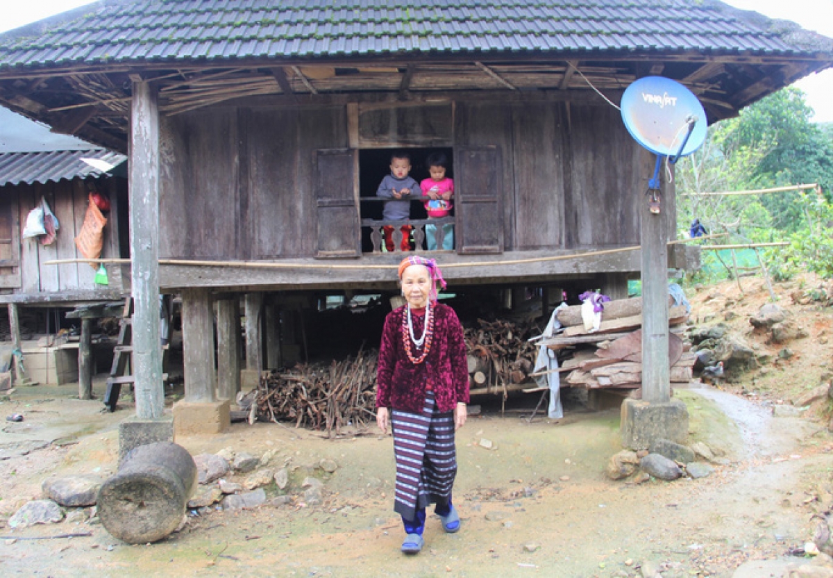 Già làng Hồ Thị Phuôn trước căn nhà sàn truyền thống của mình