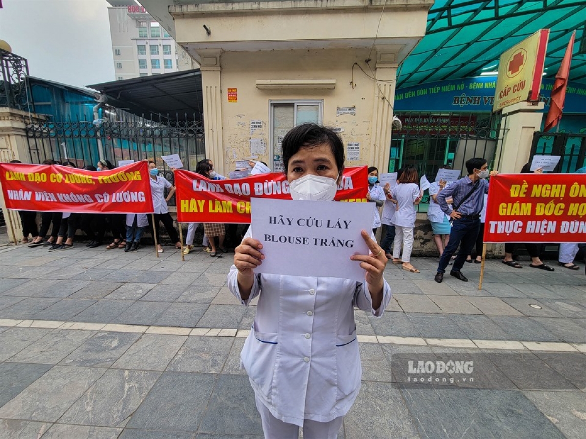 Vì bị nợ lương, các nhân viên Bệnh viện Tuệ Tĩnh xuống đường chăng băng rôn kêu cứu đầy xót xa “hãy cứu lấy blouse trắng”. Ảnh: LDO