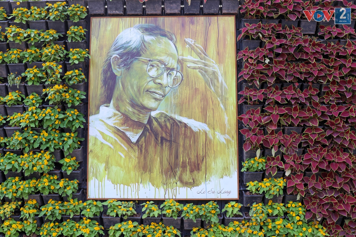 Bức tường gắn nhiều loại hoa tươi dài hàng chục mét, trên treo nhiều tấm ảnh chân dung cố nhạc sĩ Trịnh Công Sơn.