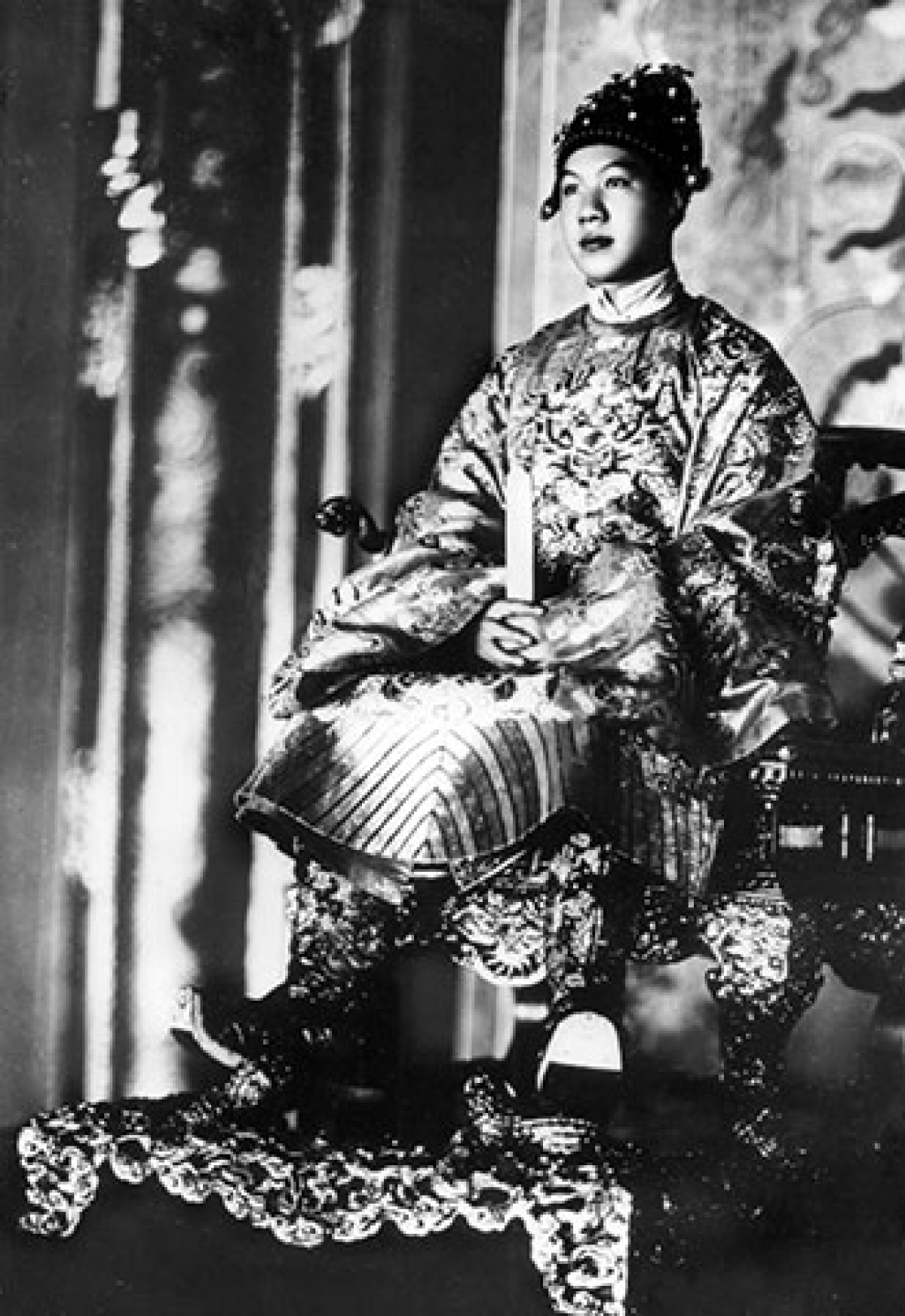 Vua Bảo Đại trong trang phục đại triều, đầu đội mão (mũ) cửu long, ngự trên ngai vàng trong điện Thái Hòa.