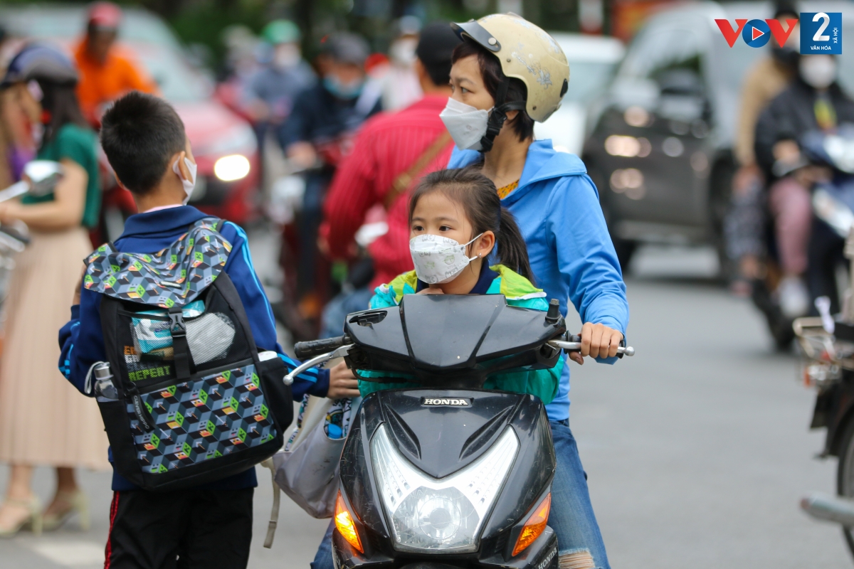 Cha mẹ không quên mặc cho con trẻ chiếc áo khoác gió trước khi đến trường.