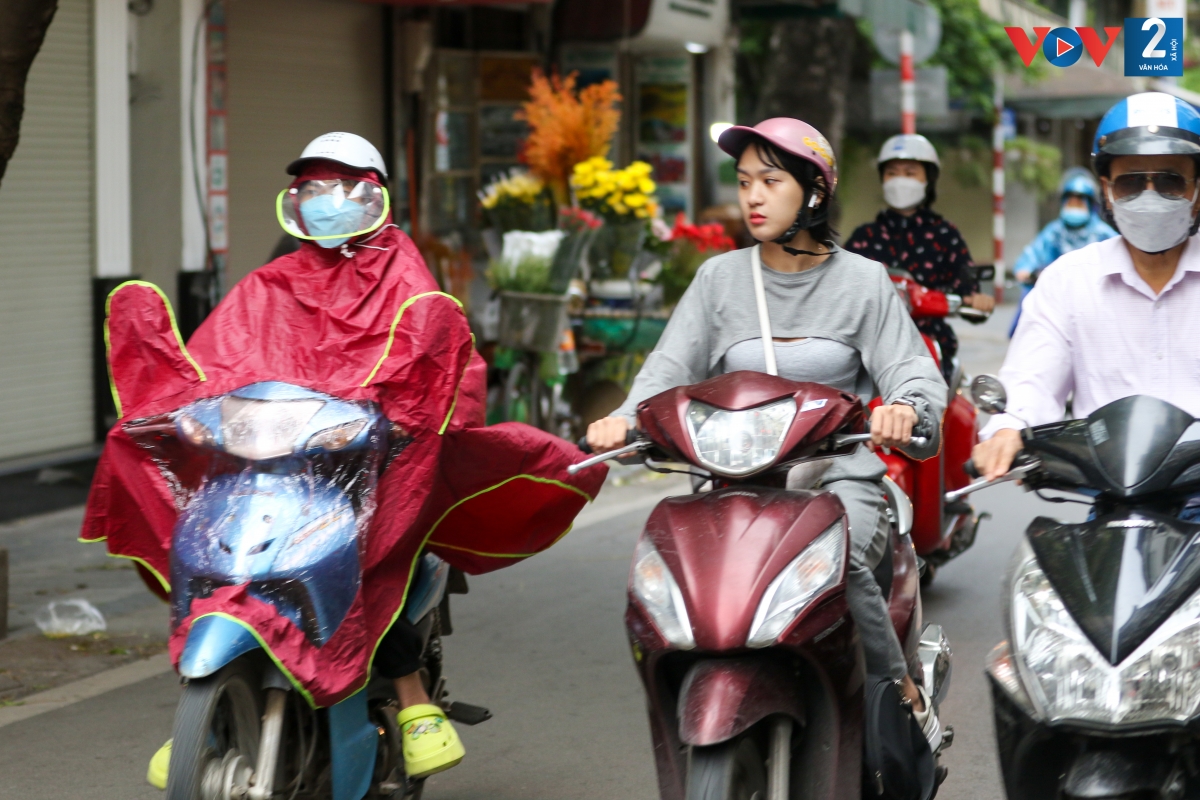 Nhiều người dân chưa kịp mang theo áo ấm, phải mặc áo mưa để di chuyển trên đường.