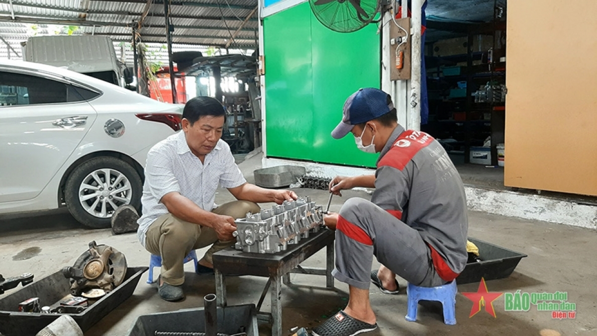 Cựu chiến binh Trần Nhật Ninh (bên trái) hướng dẫn học viên thực hành sửa chữa ô tô.