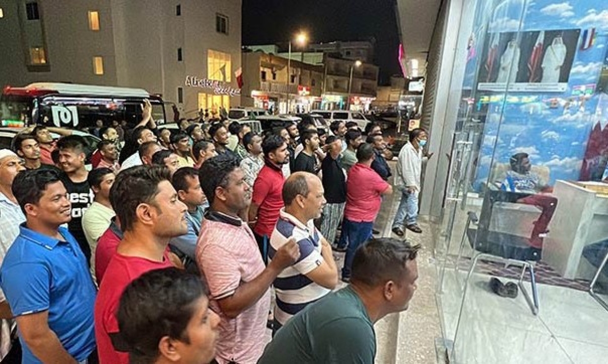 Những người lao động giản đơn thu nhập thấp ở Doha xem World Cup qua một màn hình tivi nhỏ qua cửa kính