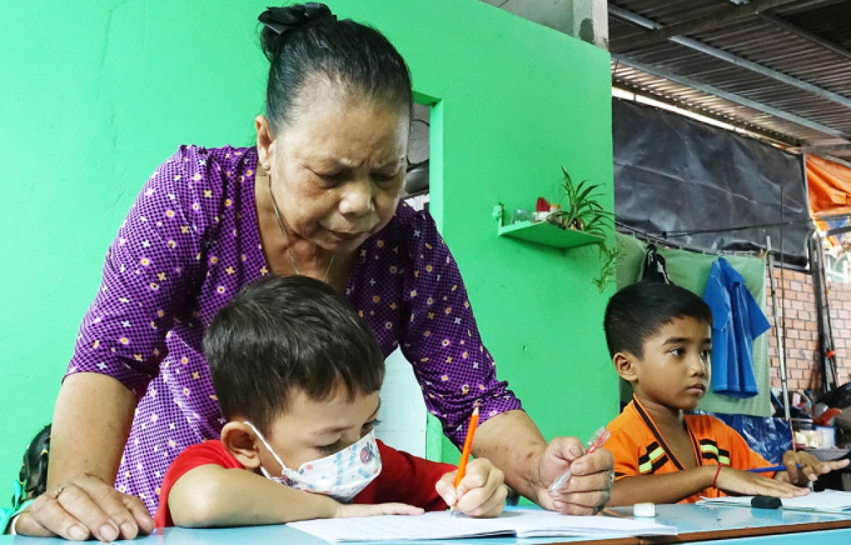 Bà Trần Thị Mươn dạy trẻ em viết chữ tại lớp học tình thương của mình.