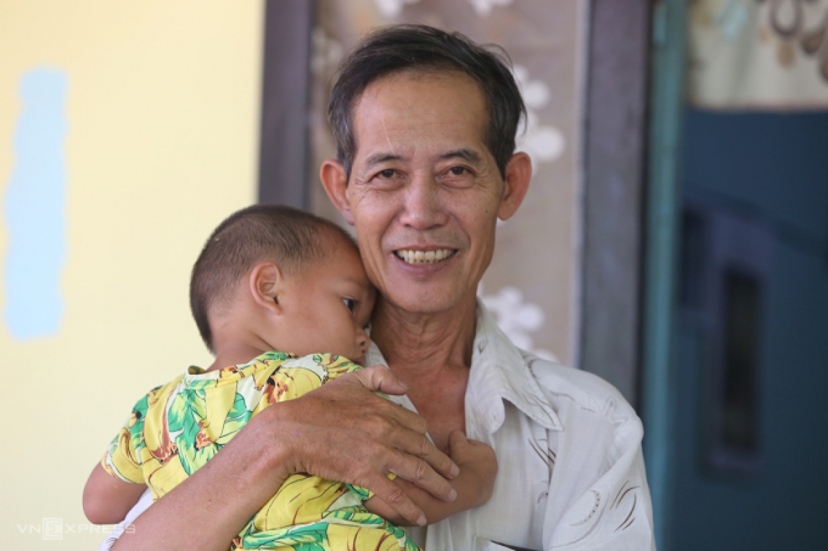 Ông Huỳnh Tấn Hùng đang bồng bé trai ngủ tại Trung tâm nuôi dưỡng trẻ em có hoàn cảnh đặc biệt khó khăn huyện Phú Ninh