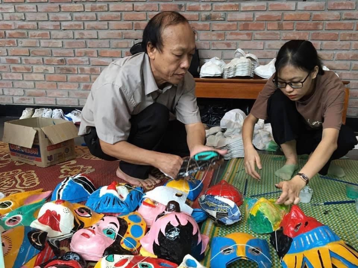 Nghệ nhân Nguyễn Văn Hòa với những chiếc mặt nạ giấy bồi. Ảnh: BTDTHVN