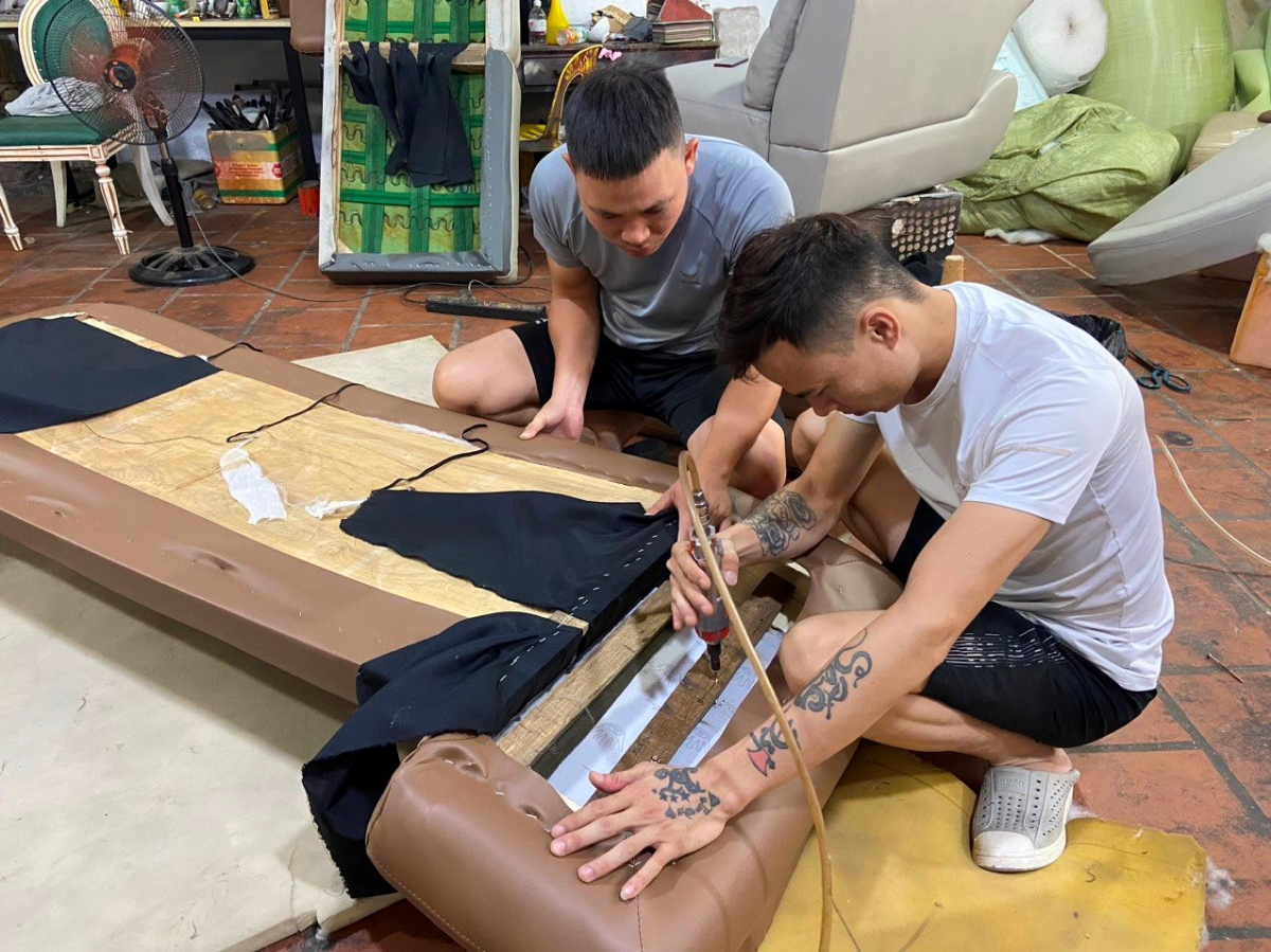 Nguyễn Văn Băng (áo trắng) cùng anh Nguyễn Văn Phúc đang sửa một sản phẩm đồ da cho khách hàng