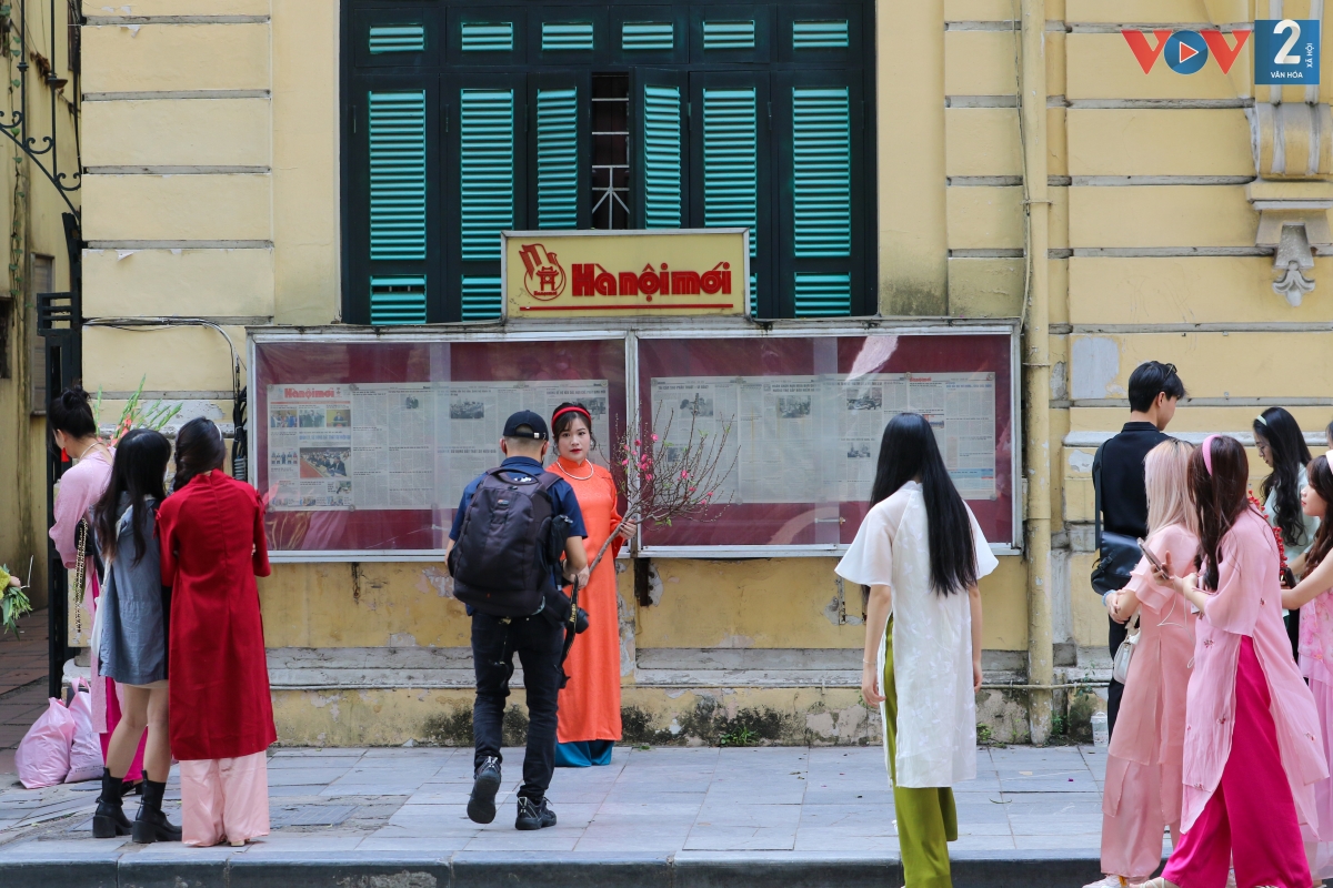 Một địa điểm chụp ảnh áo dài khác ở Hà Nội là tòa soạn báo Hà Nội Mới. Chỉ với một bức tường vàng, khung cửa xanh cùng tủ báo lồng kính tạo nên một khung hình độc đáo, mang màu sắc cổ kính khiến các bạn trẻ thích thú.