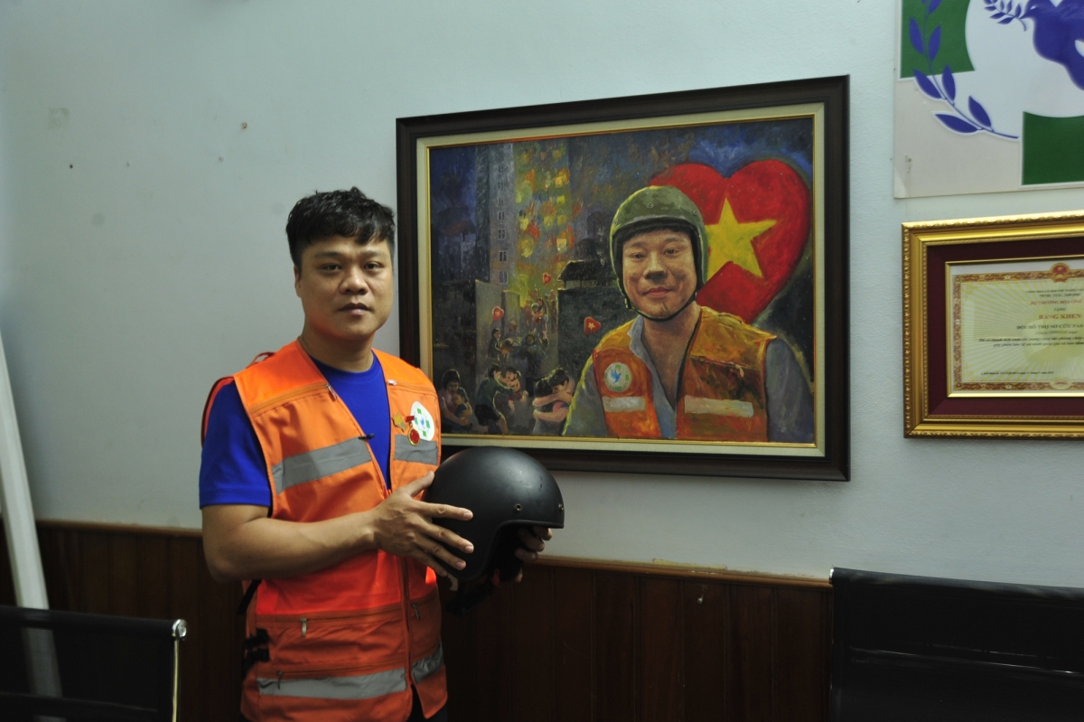 Anh Phạm Quốc Việt bên bức tranh vẽ cảnh cứu người tại chung cư mi ni Khương Hạ