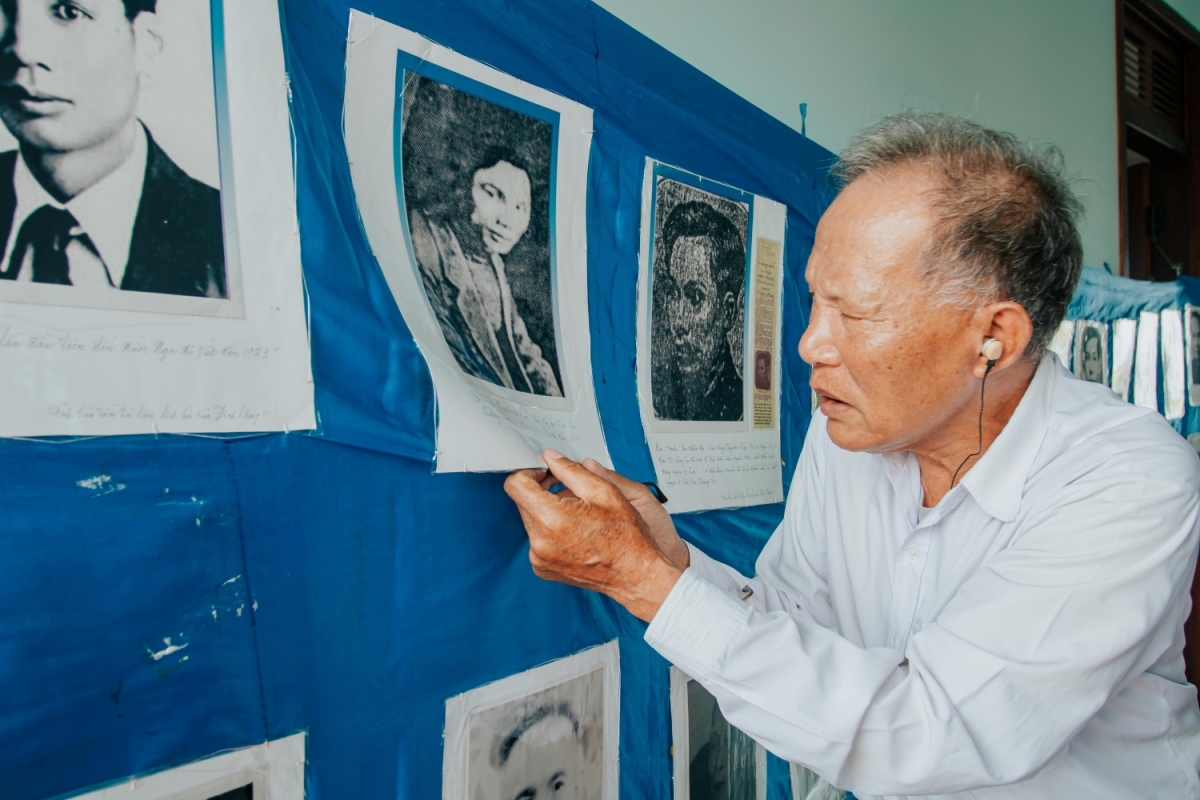 Ông Phong dán những tấm ảnh về Bác Hồ lên băng vải dài để thuận lợi cho việc trưng bày, giới thiệu