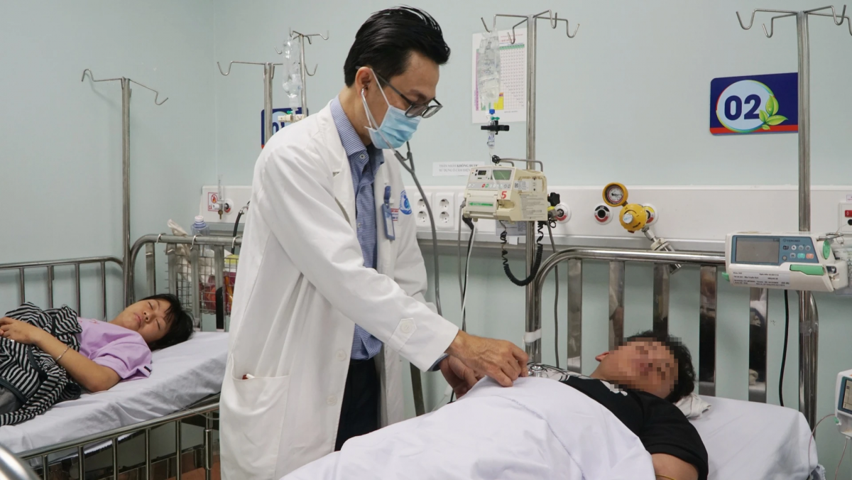 Bác sĩ Nguyễn Minh Tuấn thăm khám cho bệnh nhi bị sốc sốt xuất huyết nặng đang được điều trị tại khoa. Ảnh: Nguyễn Thuận