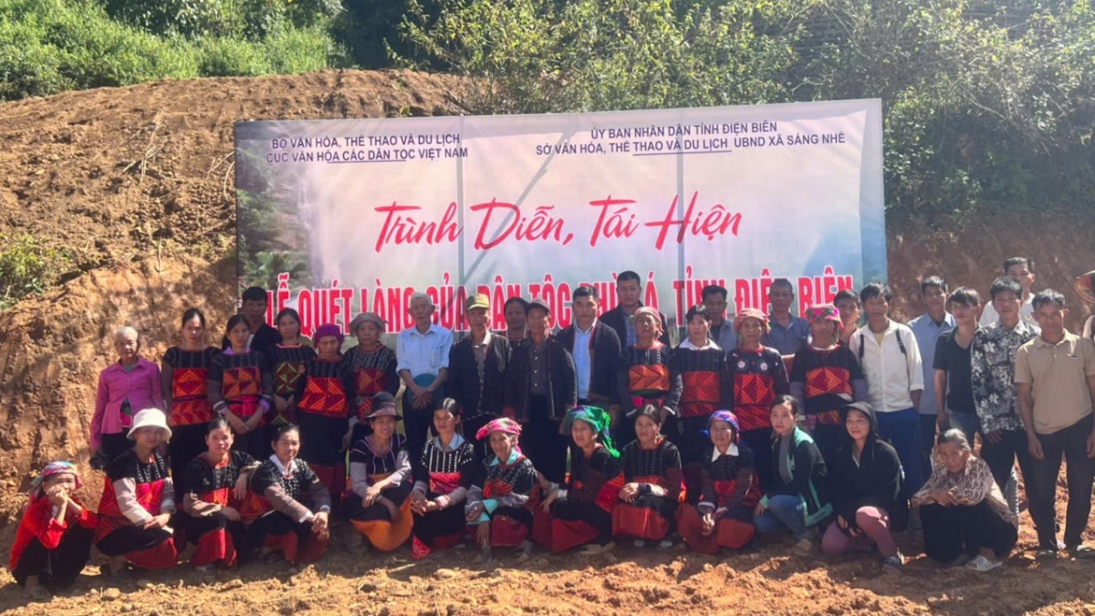 Ảnh chụp tập thể các nghệ nhân và học viên Phù Lá ngoài trời trong buổi "Trình diễn, Tái hiện Lễ Quét làng", với phông nền lớn ghi rõ tên và đơn vị tổ chức sự kiện . Các học viên thể hiện sự quyết tâm trong việc phục hồi và phát huy nghi lễ độc đáo của dân tộc mình. Nguồn: Ảnh do đơn vị tổ chức cung cấp.