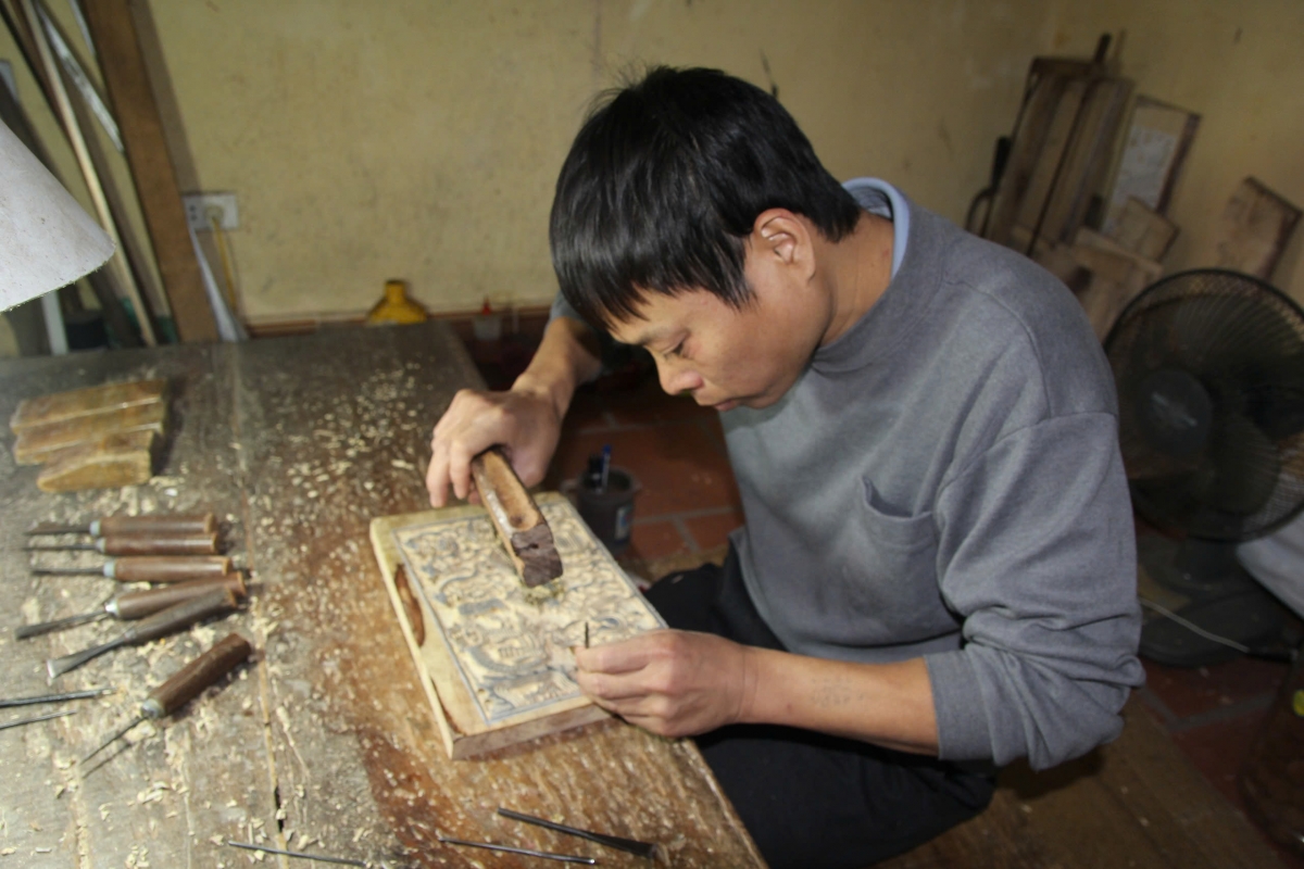 Người thợ khắc tấm ván in tranh ở làng tranh Đông Hồ. (Ảnh: Cục Di sản văn hóa)