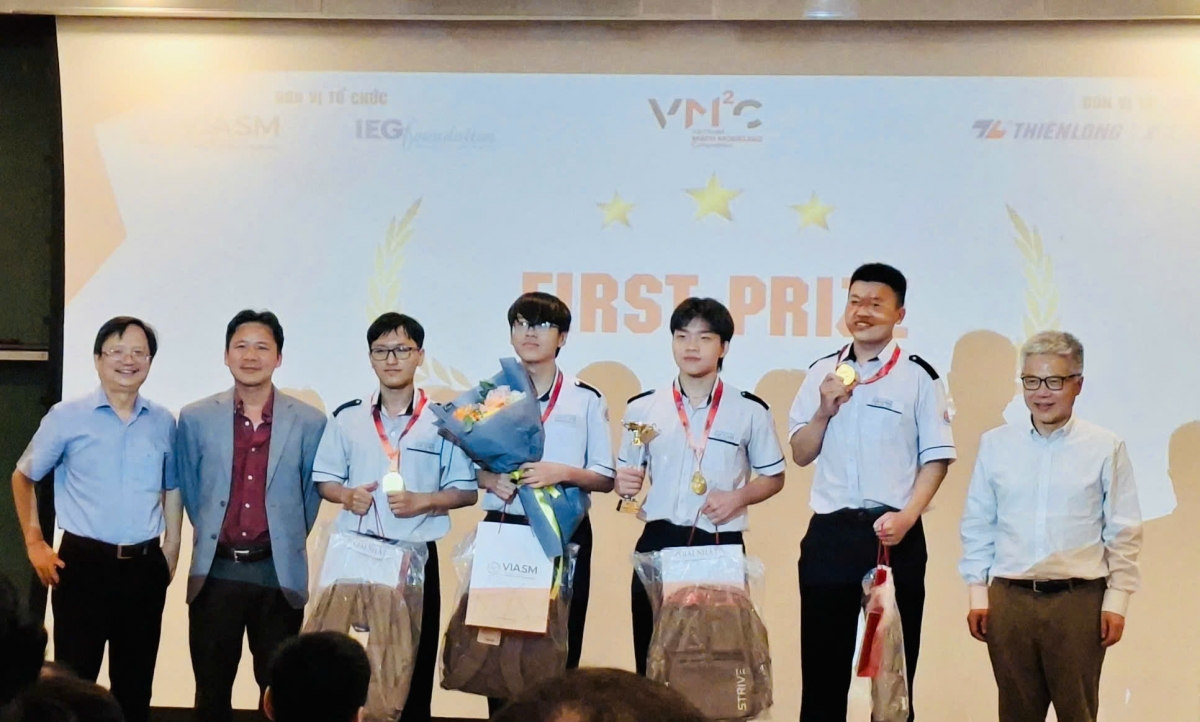 GS Ngô Bảo Châu (ngoài cùng bên phải) Giám đốc Khoa học VISAMS và GSTS Vũ Hoàng Linh - Chủ tịch Hội Toán học Việt Nam (ngoài cùng bên trái) trao cup và tặng hoa chúc mừng đội đạt giải nhất cuộc thi 
(Ảnh: Thu Lương )