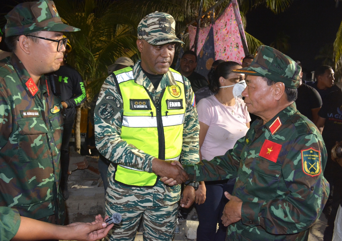 Thiếu tướng Phạm Văn Tỵ, Phó cục trưởng Cục Cứu hộ-Cứu nạn, Bộ Tổng Tham mưu, Trưởng đoàn Việt Nam trao đổi với Tư lệnh Lực lượng dân quân Venezuela Nayade Lockiby Belmonte tại hiện trường - Ảnh: Hoàng Vũ.