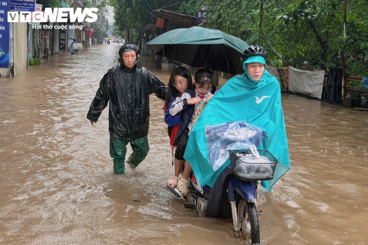 Phụ huynh vất vả đưa con đi học giữa đường ngập úng do mưa lớn tại Hà Nội, ảnh: VTC News